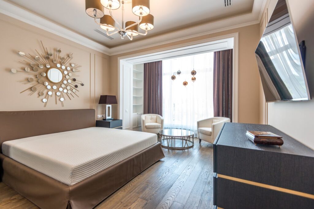 Contemporary hotel room with stylish furnishings and decor featuring a chic chandelier and large window.